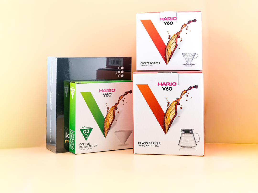 HARIO V60 Pro Brew Set components including dripper, glass server, and coffee filters on a pastel background.