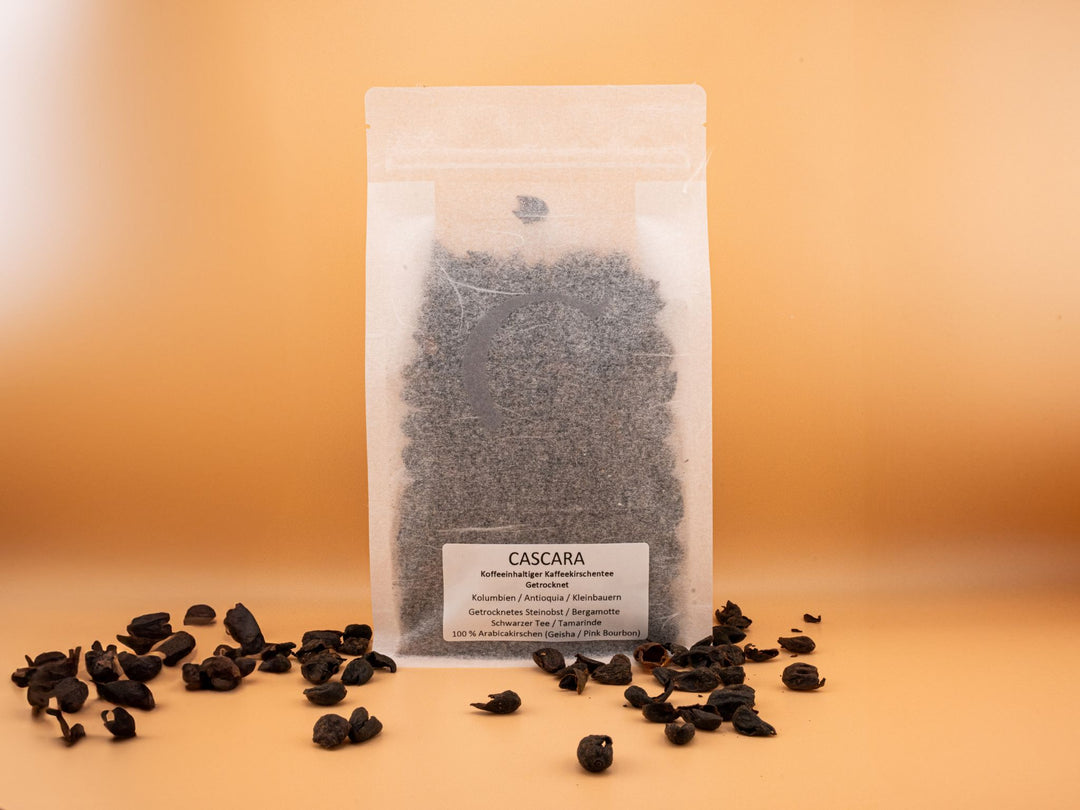 Cascara tea blend in a clear package, showcasing dried coffee cherries with spilled beans on a warm background.