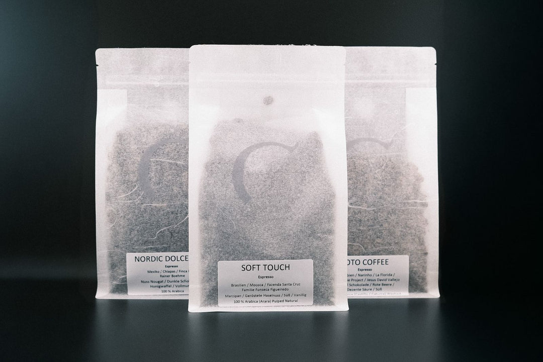 Drei Kaffeepackungen mit Etiketten "Soto Coffee", "Soft Touch" und "Nordic Dolce" vor schwarzem Hintergrund, mit Angaben zu Herkunft, Sorte und Geschmacksprofil.